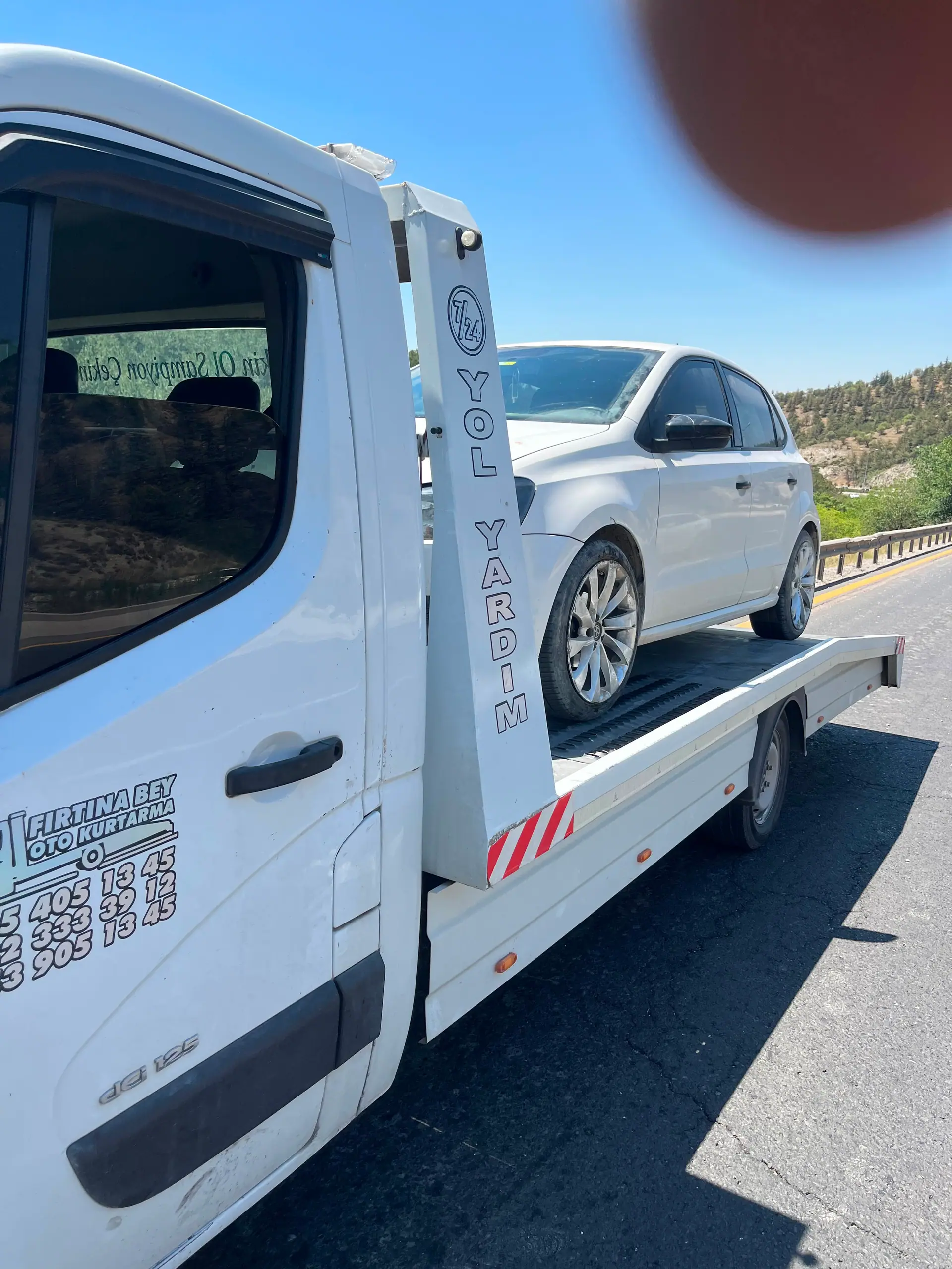 Karayolu üzerinde çekici platformunda taşınan beyaz hatchback otomobil